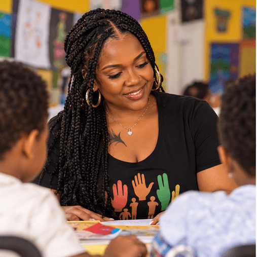 The founder of Blulifestyles Foundation working alongside young people at a table in a colorful classroom.
